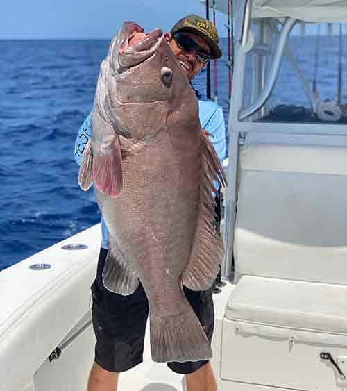 man in blue holding a large fish
